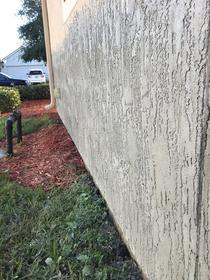 A stucco wall against a red-mulch bed