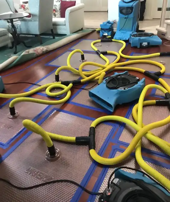 Drying mats and yellow hoses laid across a floor after water damage
